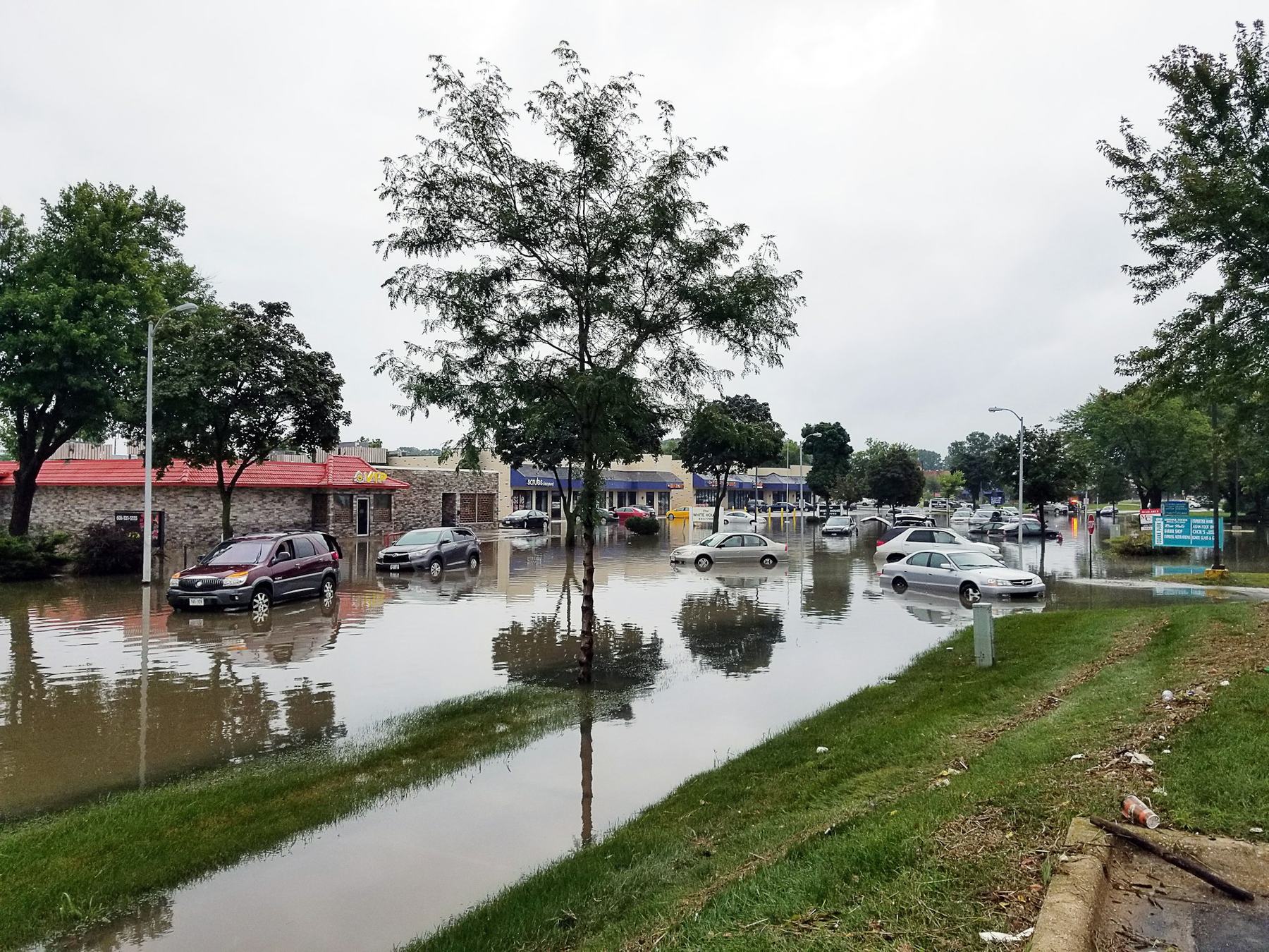 Cars standing in floodwater outside a row of shops